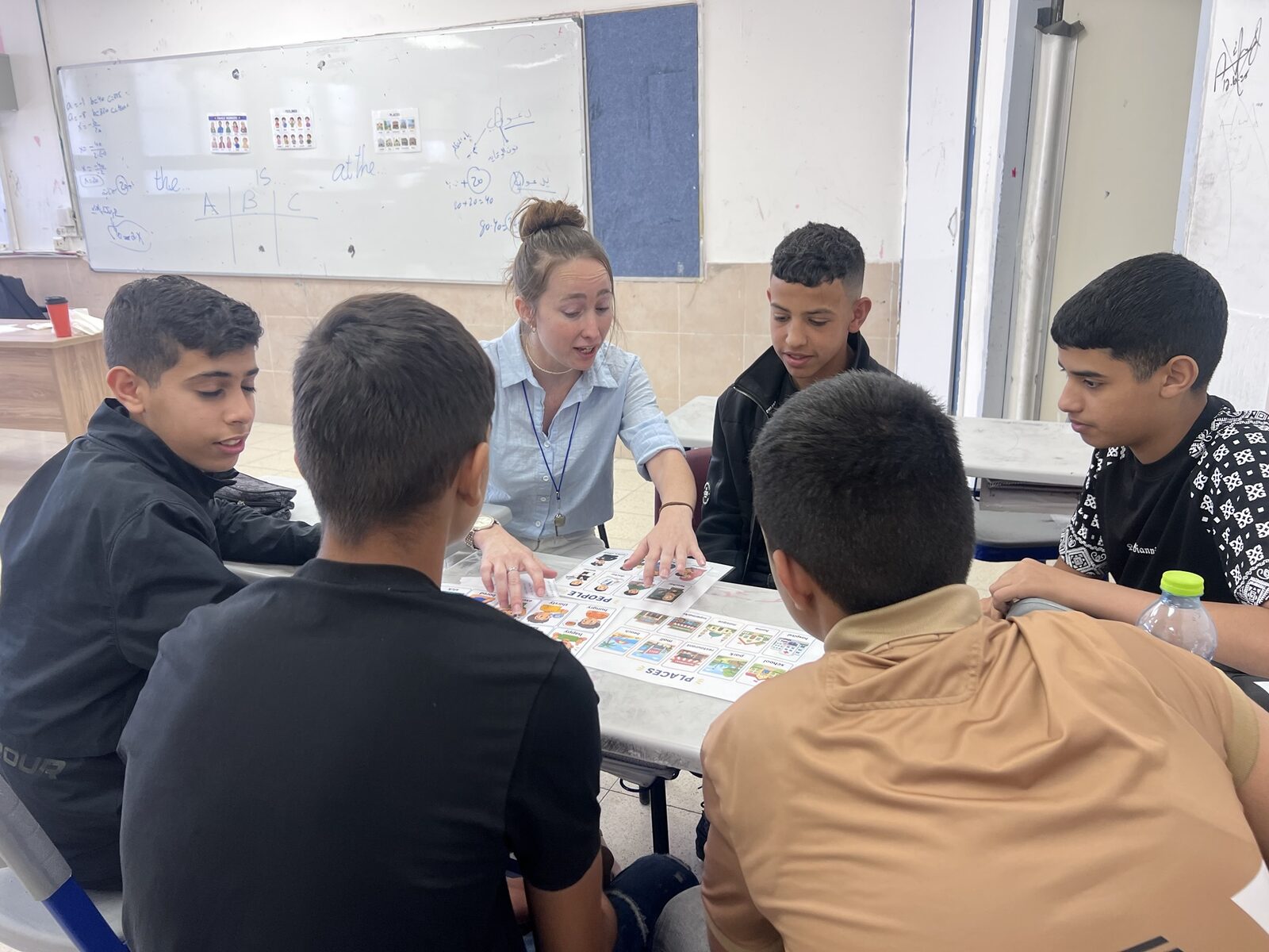 מורה ותלמידים סביב שולחן משחקים משחק אוצר מילים בכרטיסים מצוירים